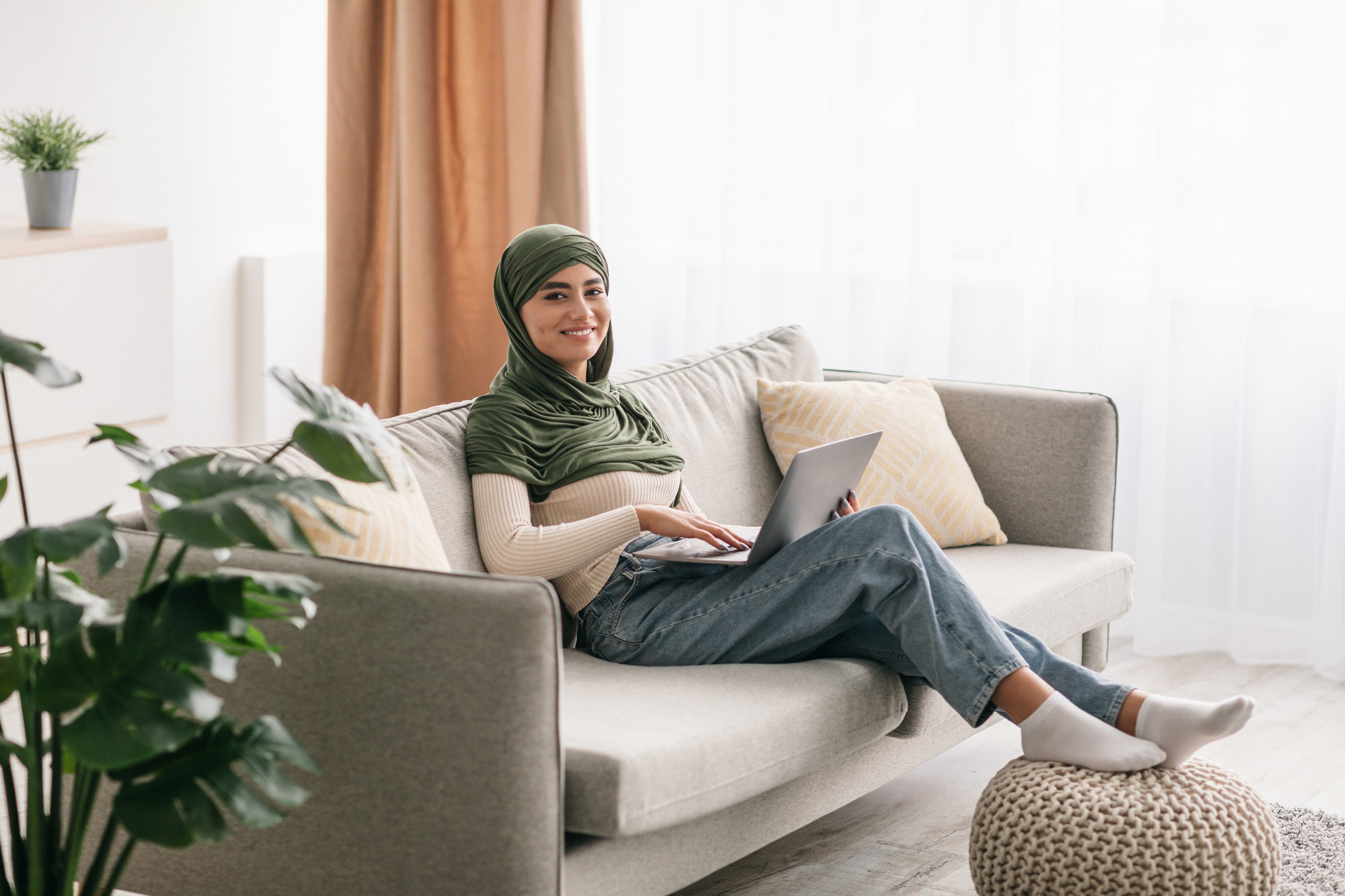 AAT student in green hijab studying on her couch 