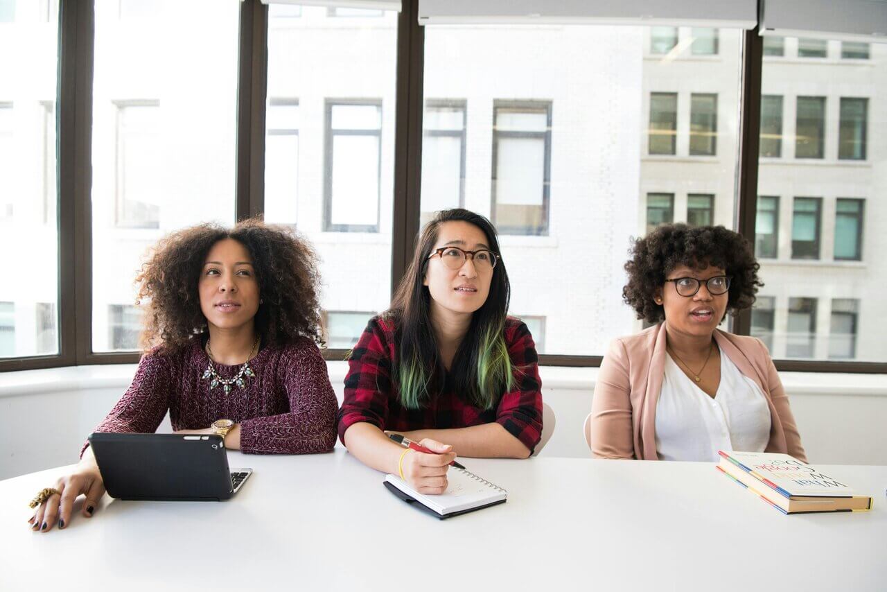 Three women of colour sitting at desk in office