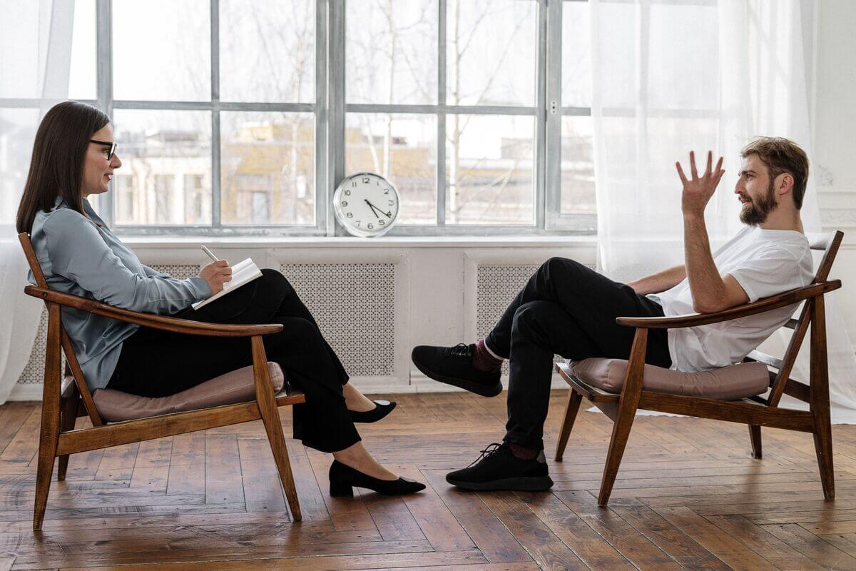 Professional coach speaking to a coachee while sitting in comfortable chairs