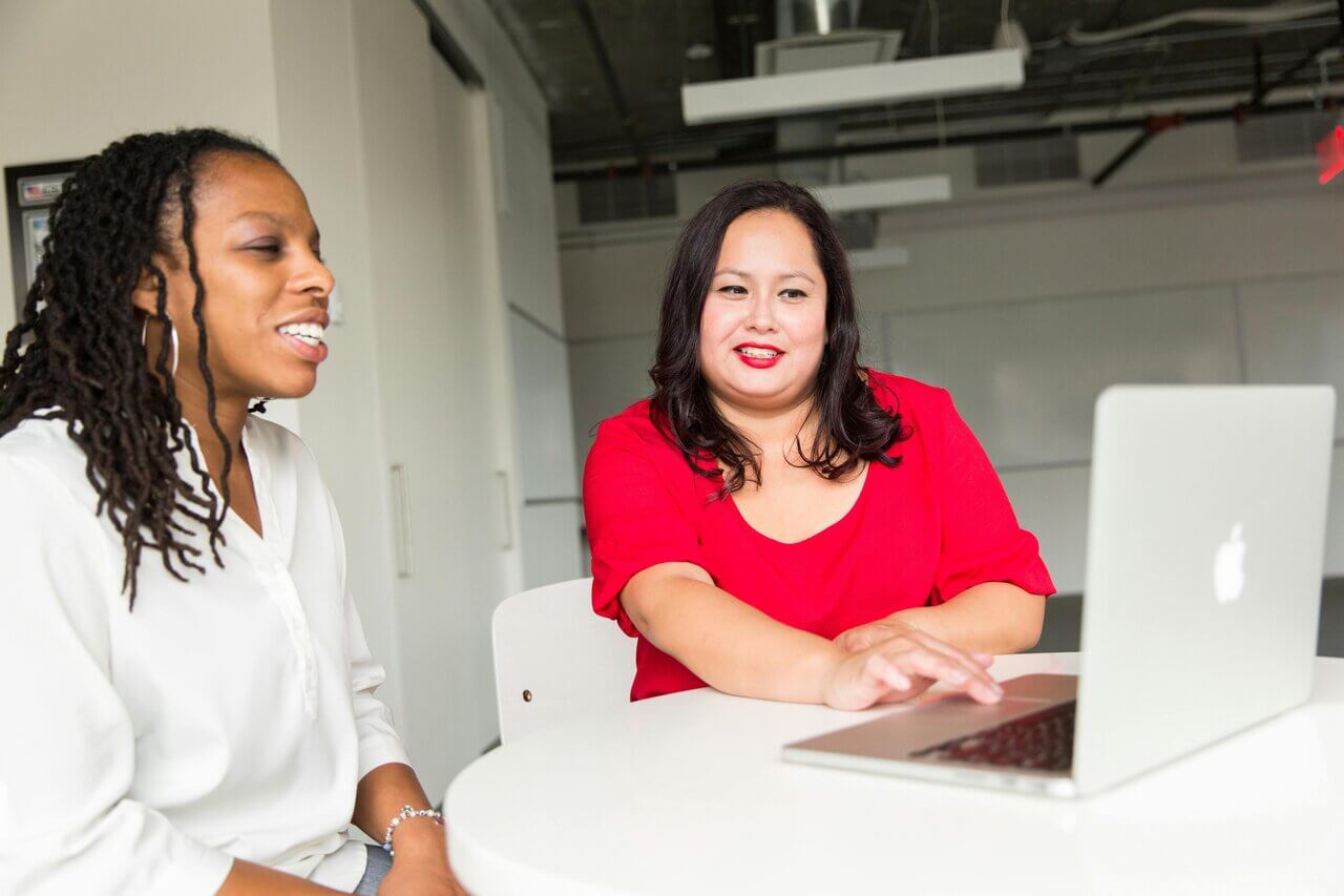 Two women professionals with laptop at desk in office
