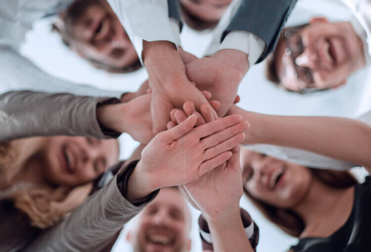 6 employees putting hand together smiling 